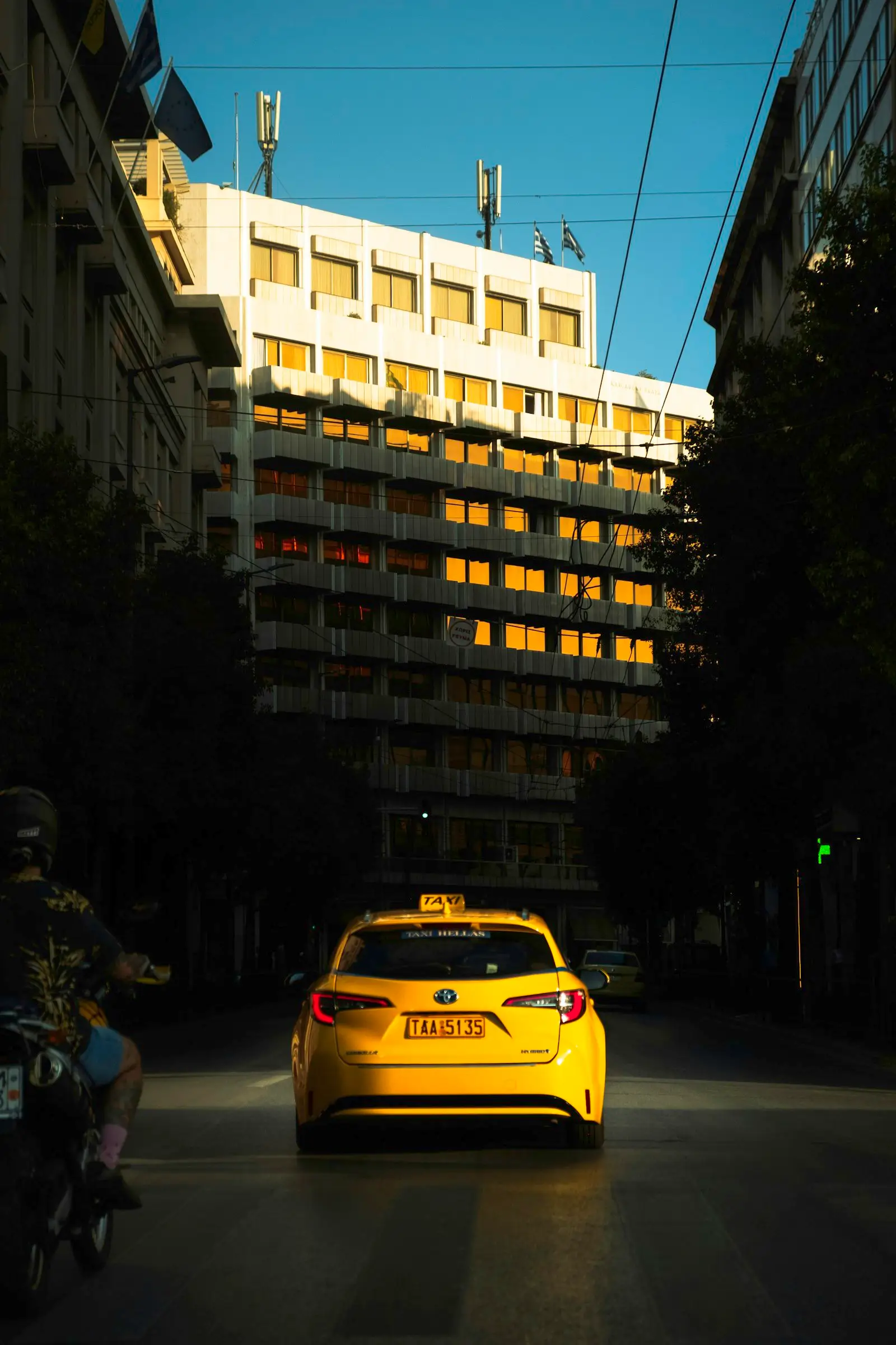 A yellow Athens taxi on a sunlit city street