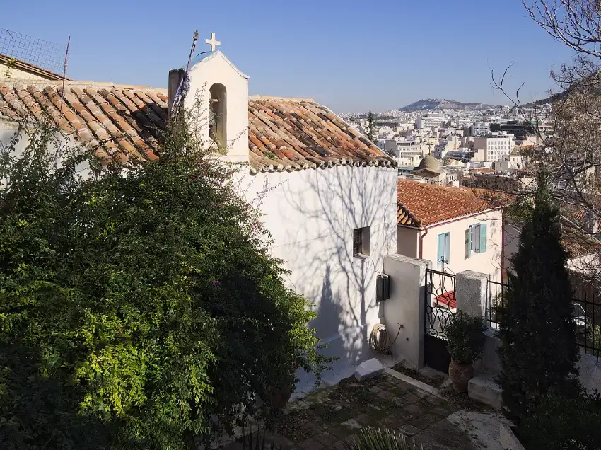 A small whitewashed church on the Acropolis slope at the edge of Anafiotika, with low island-style houses around it