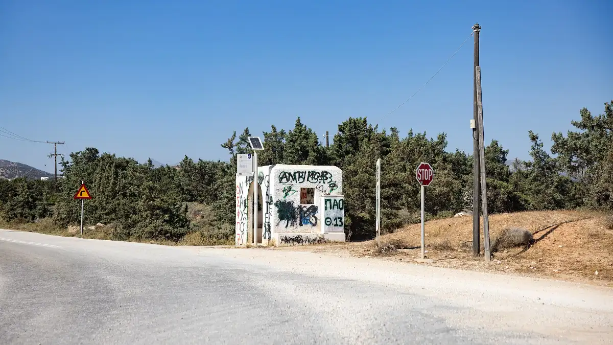 A concrete bus shelter on the verge of an empty road at Alyko on the south-west coast of Naxos