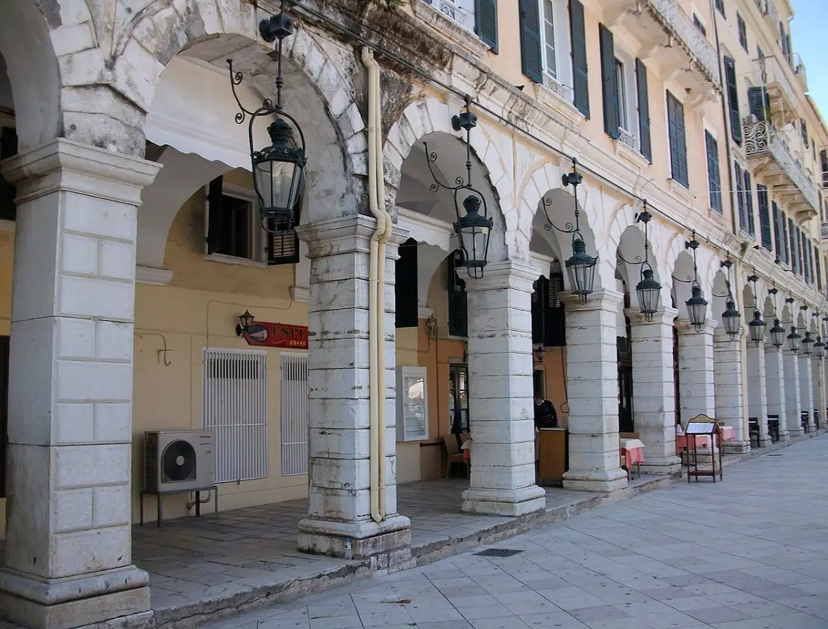 The Liston in Corfu, a run of tall arcaded arches on square piers with hanging lanterns above an empty stone terrace