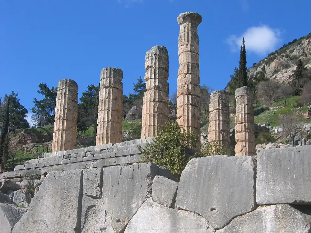 The stone-paved Sacred Way climbing between ruined treasury foundations toward the temple terrace at Delphi