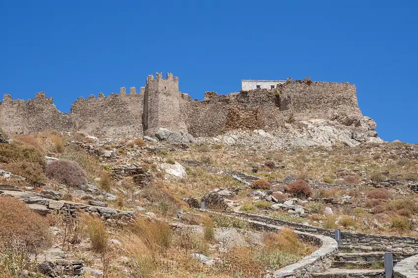 The red-brown walls and square tower of Castello Rosso on the ridge above Karystos, southern Evia, under a deep blue sky
