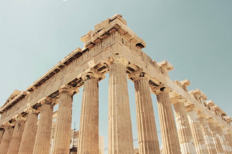 Ancient marble temple columns against a blue Greek sky