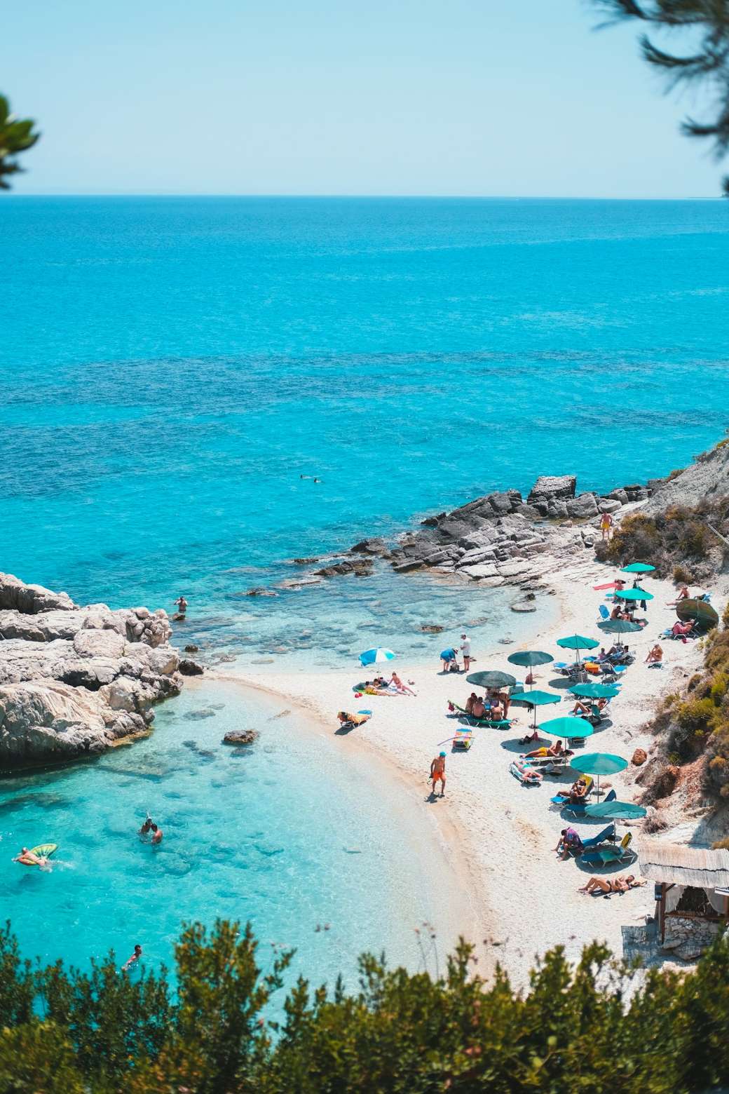A turquoise Greek bay with a beach below dry hills