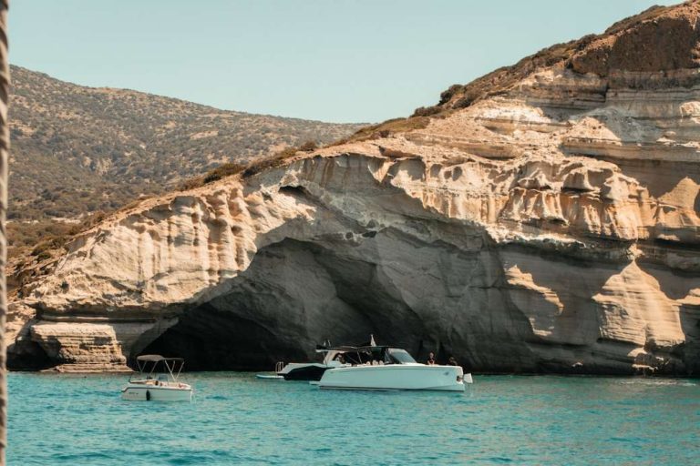 A small excursion boat cruising past white sea-caves