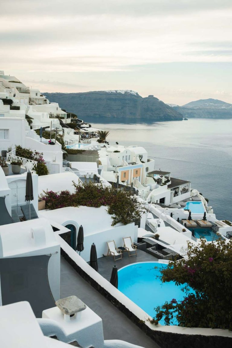 Whitewashed Cycladic hotel buildings with a pool overlooking the sea