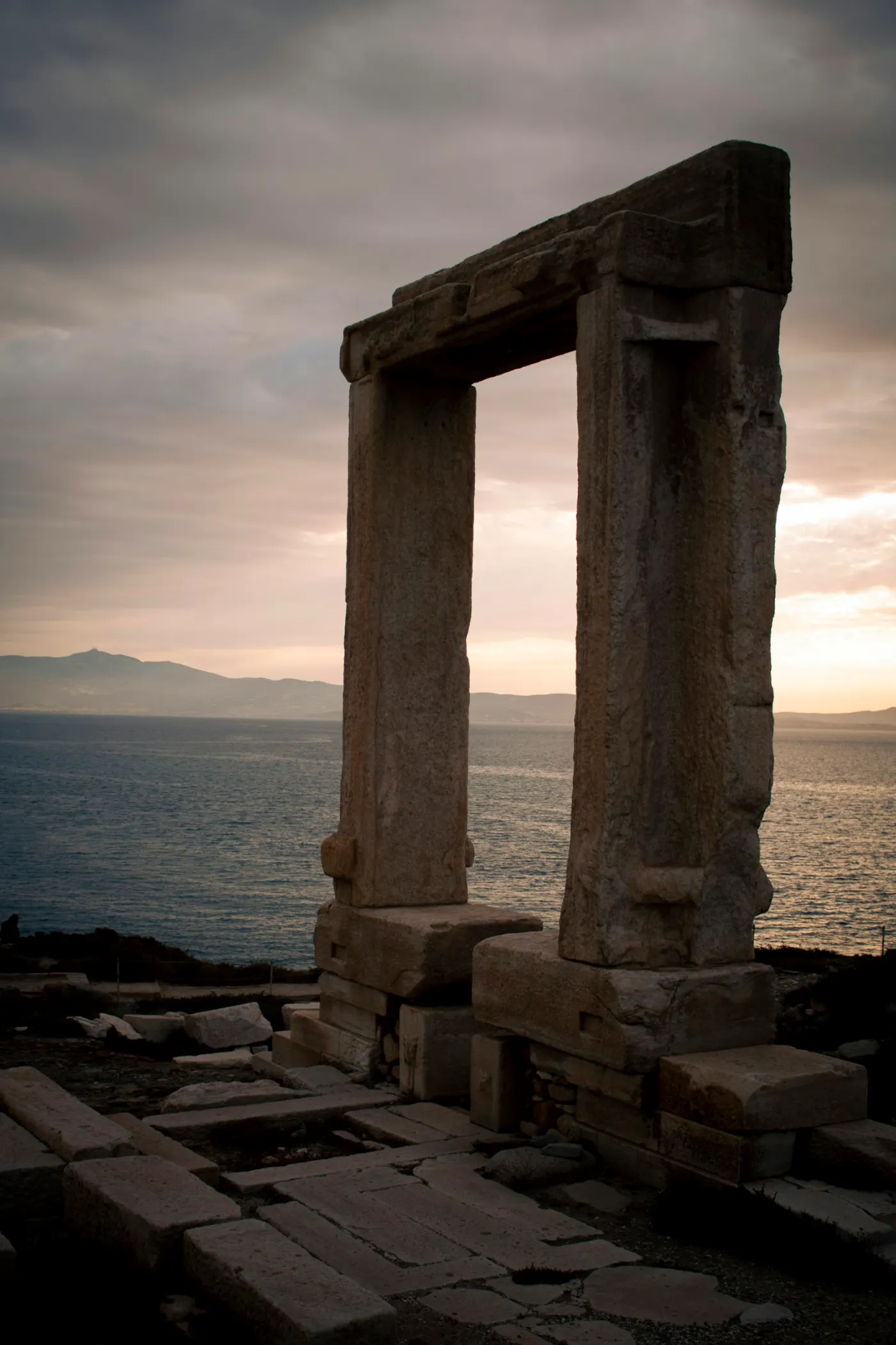 The Portara on Naxos - a free-standing marble doorway of two uprights and a lintel on a low islet, framing the sea at sunset