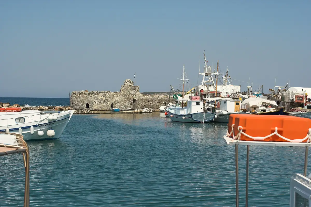 The old fishing harbour at Naoussa on Paros, with fishing boats moored either side of a ruined stone fort on the breakwater