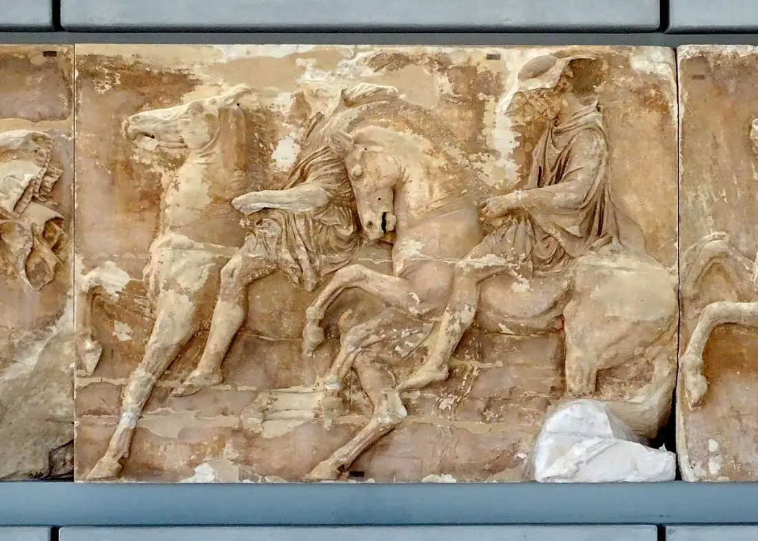 A marble block of the Parthenon frieze carved in low relief with horsemen of the Panathenaic procession
