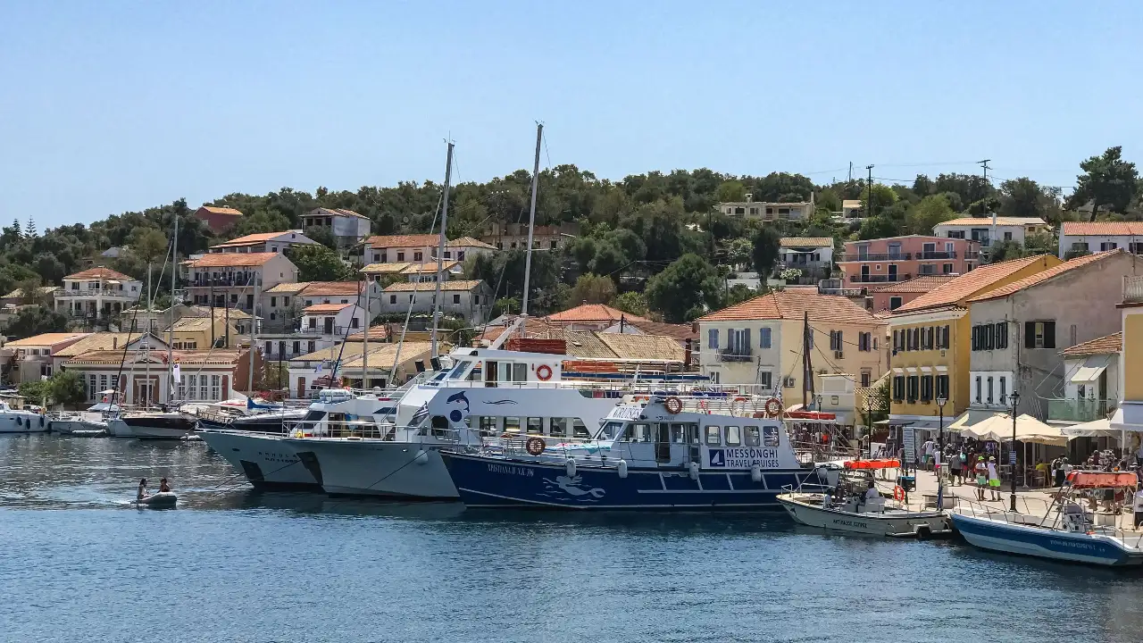 The harbour at Gaios on Paxos: boats moored along the waterfront with the town's buildings rising on the slope behind them