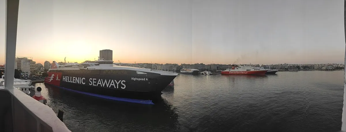 Piraeus harbour at dusk, a Hellenic Seaways fast ferry at the near quay and several more ferries moored across the basin