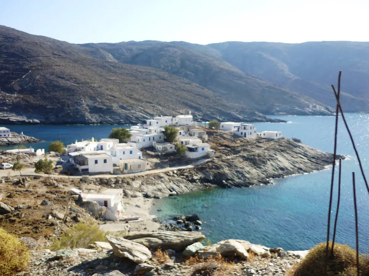 The small white settlement of Mali on the coast of Tinos, with bare terraced hills behind and an empty cove below
