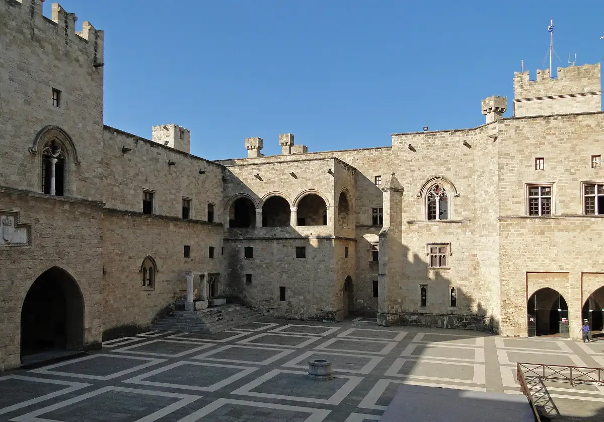 The empty main courtyard of the Palace of the Grand Masters in Rhodes: honey-coloured stone ranges around a black-and-white chequered pavement