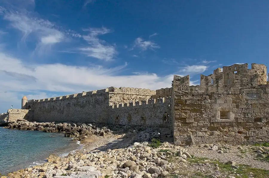 The crenellated sea-facing medieval walls of Rhodes Old Town running to a round tower, under a blue sky