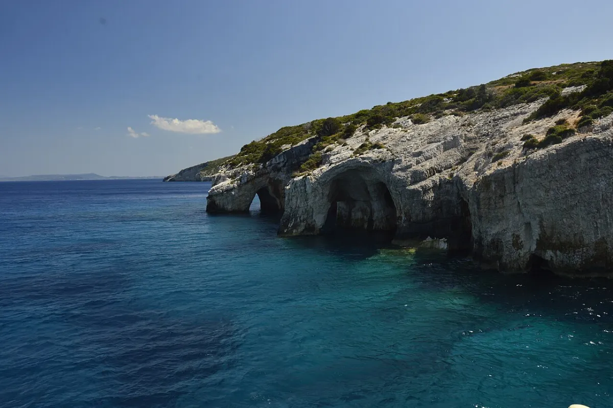A sea-carved limestone arch at the Blue Caves, Cape Skinari, with deep blue water beneath it