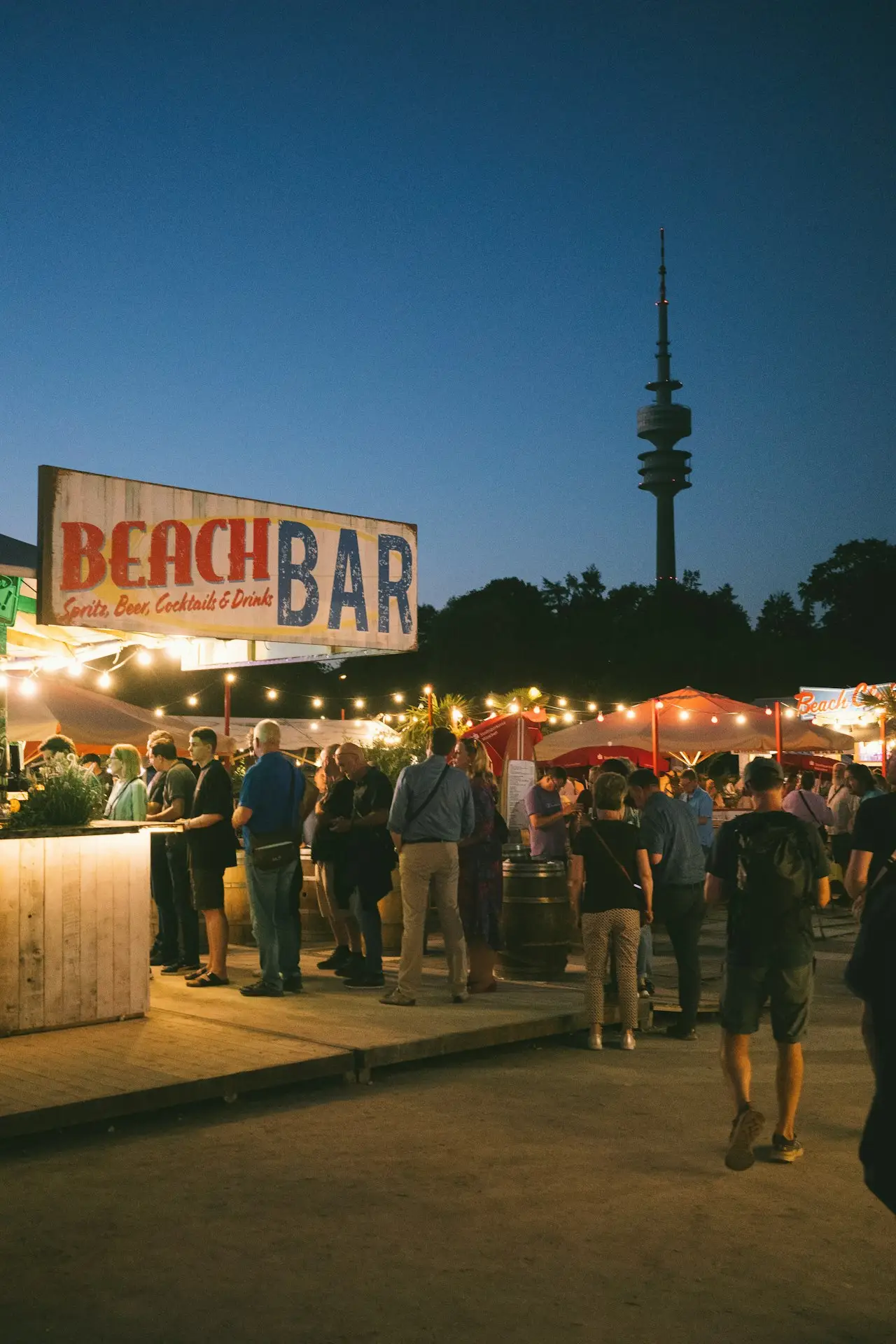 People gathered at a lit beach bar at dusk