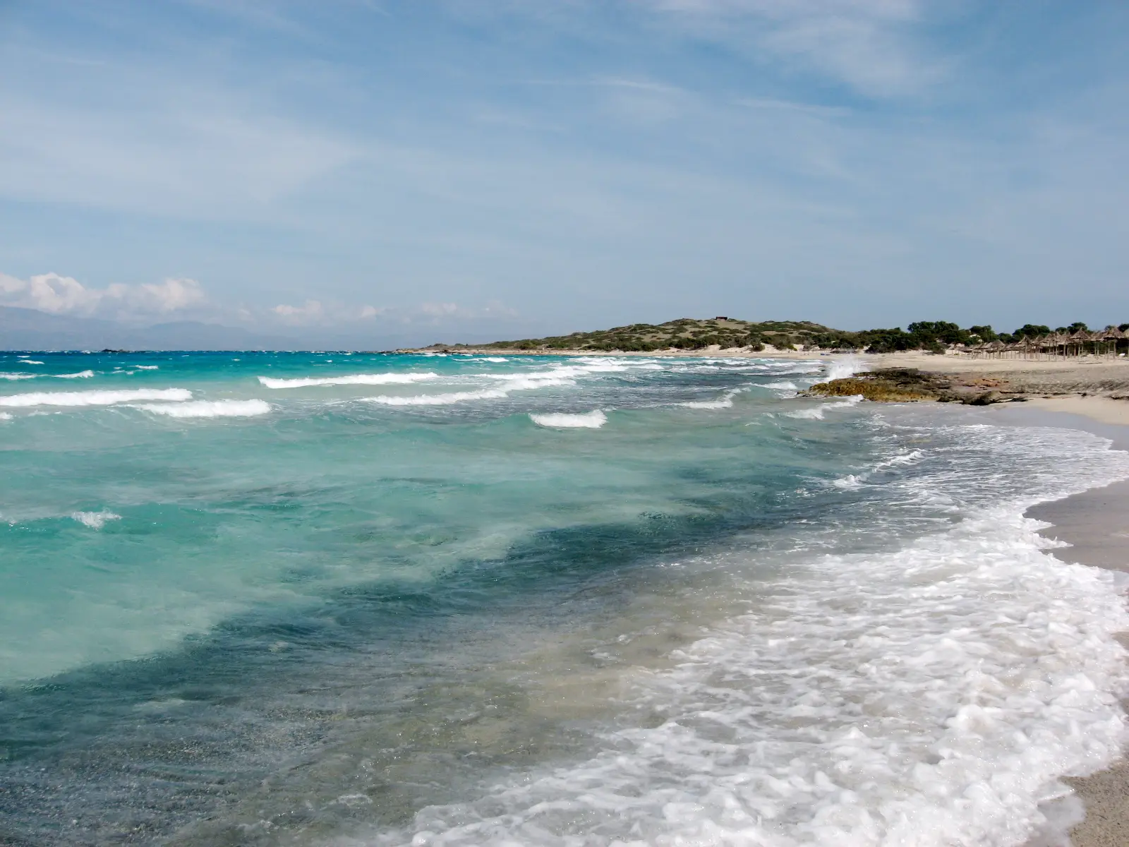 The empty shore of Chrissi island, surf breaking over pale sand