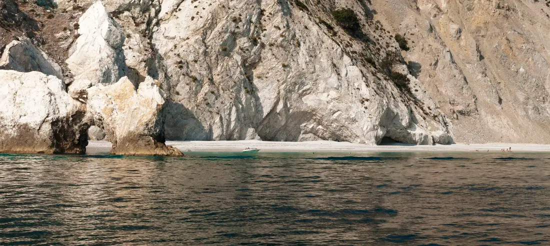 Lalaria beach on Skiathos, white pebbles below a pierced limestone cliff