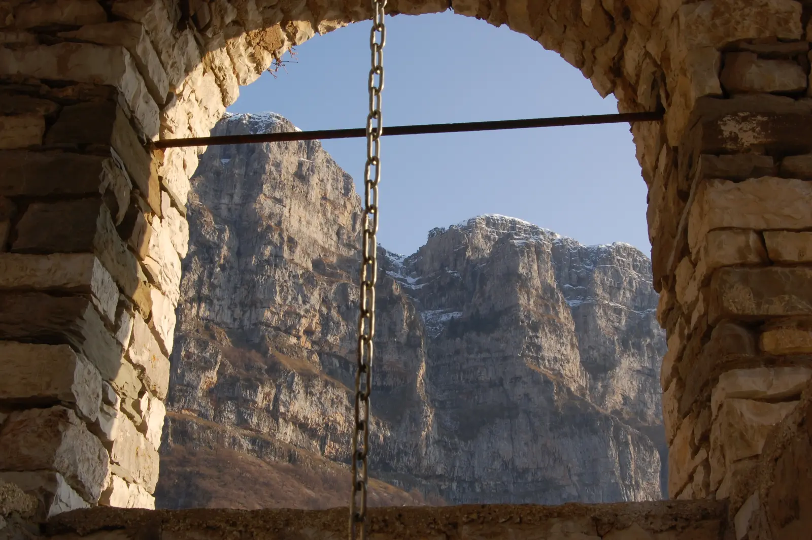 A stone arch in Mikro Papingo framing the Astraka towers behind