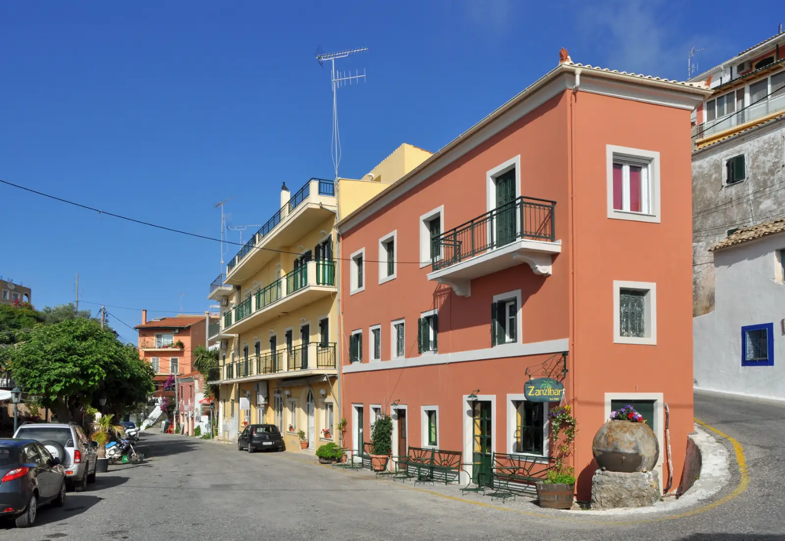 A tall pink neoclassical house on the street at Pelekas, Corfu