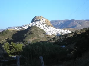 החורה של סקירוס, בתים לבנים שנשפכים במורד סלע שבראשו המבצר, והרים מאחור