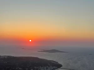 השמש שוקעת מעל הים מול קאסוס, עם הצללית הנמוכה של האיון ארמתיה באופק