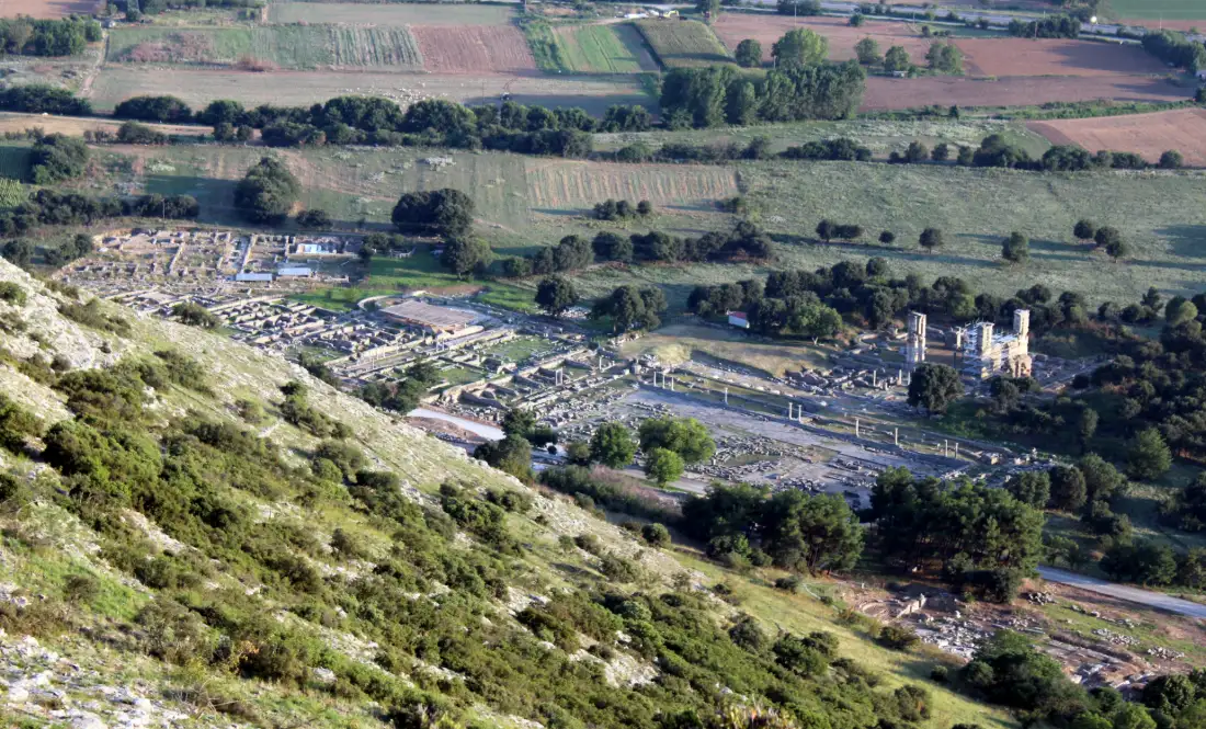 The archaeological site of Philippi seen from the hillside above, its excavated streets and foundations laid out across the plain